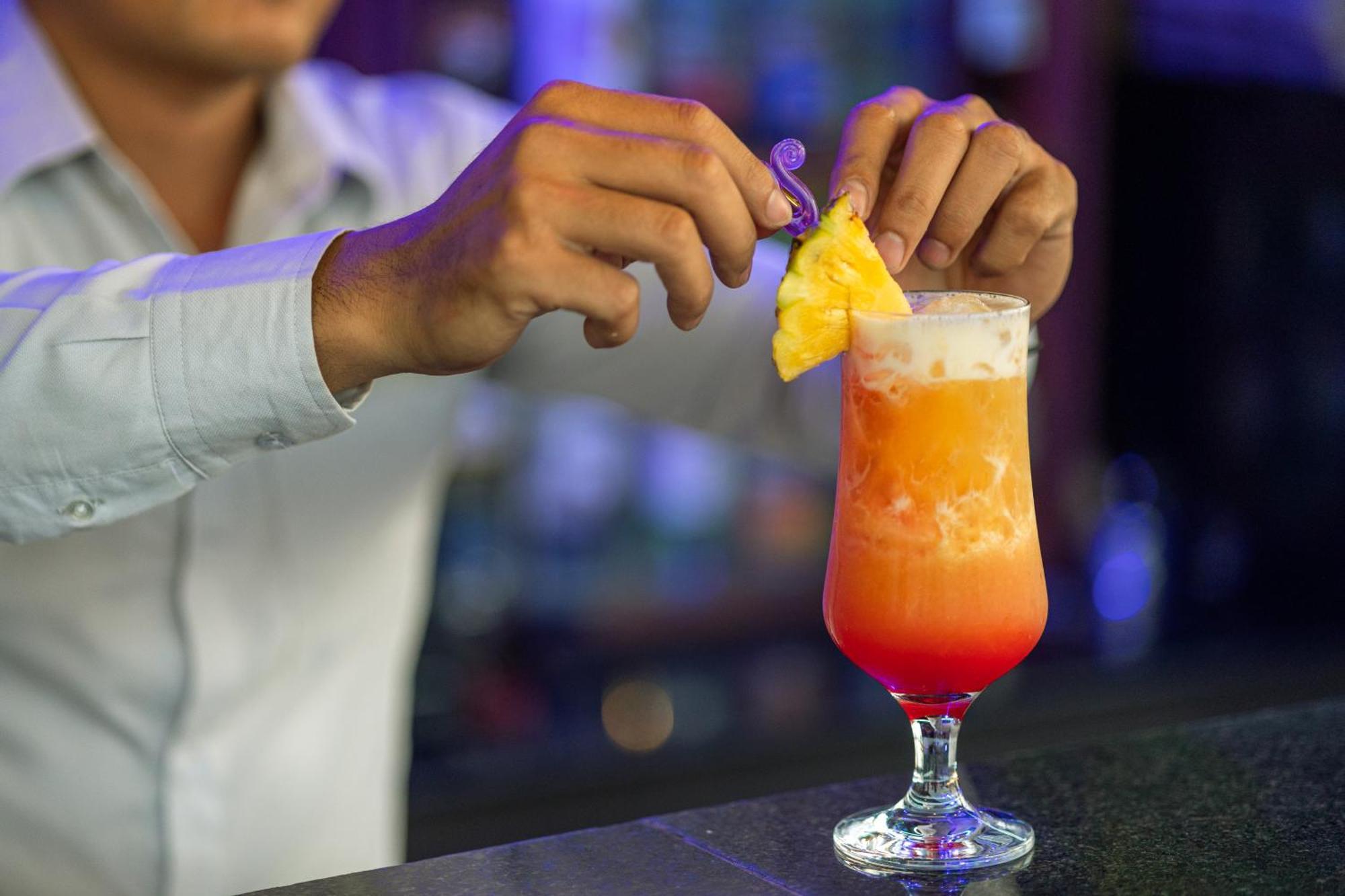 Two Seasons Siem Reap Hotel Eksteriør billede A bartender adding a pineapple wedge to a Hurricane